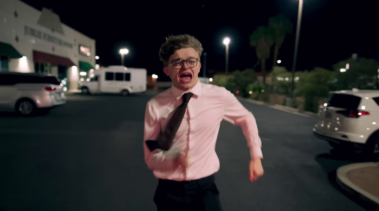 a man in a pink shirt and tie running down a street