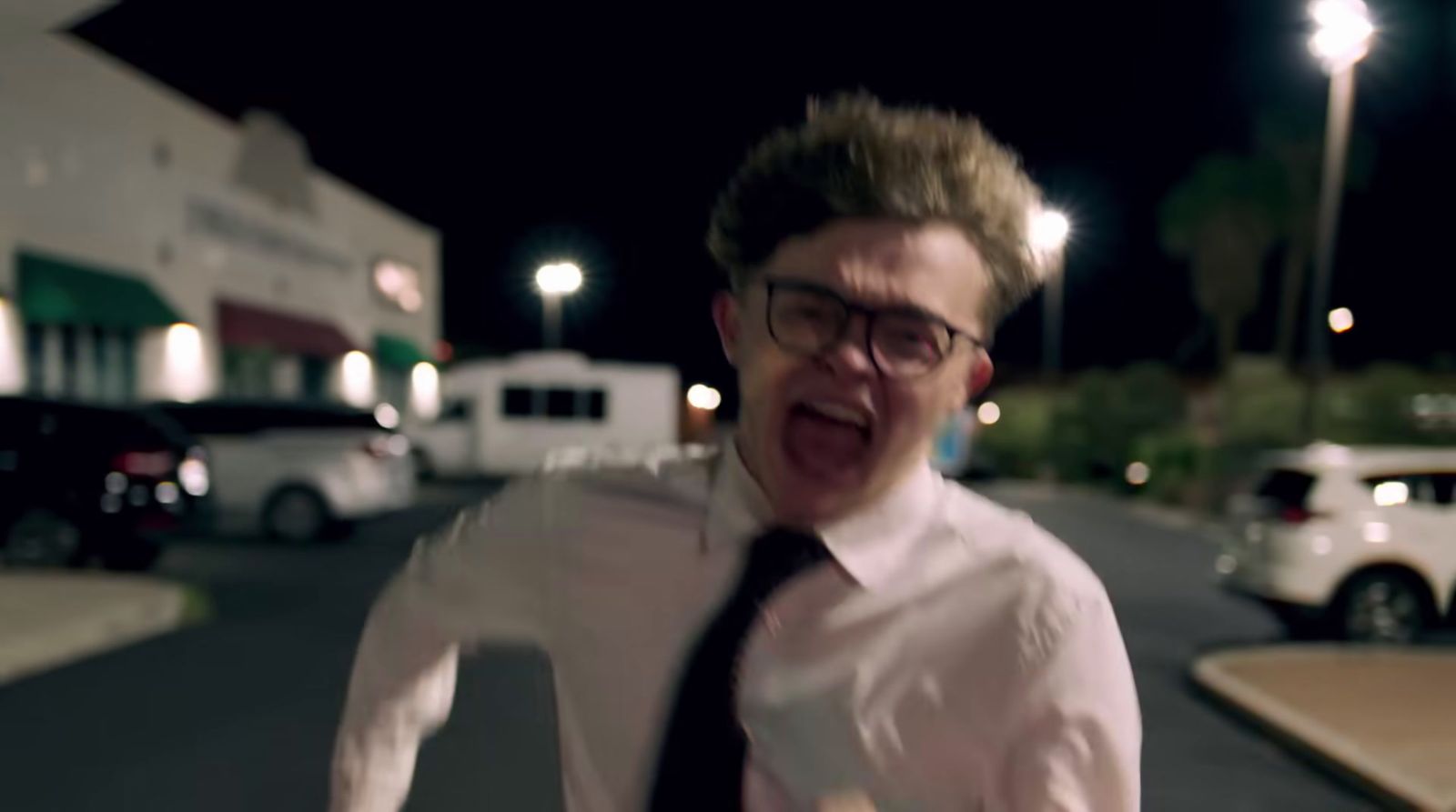 a man wearing glasses and a tie making a funny face