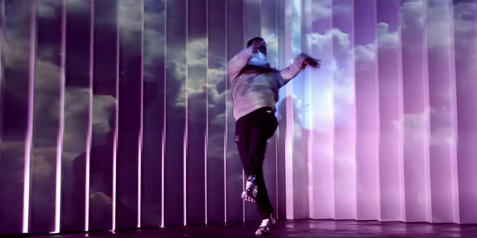 a man standing on top of a stage next to a purple wall