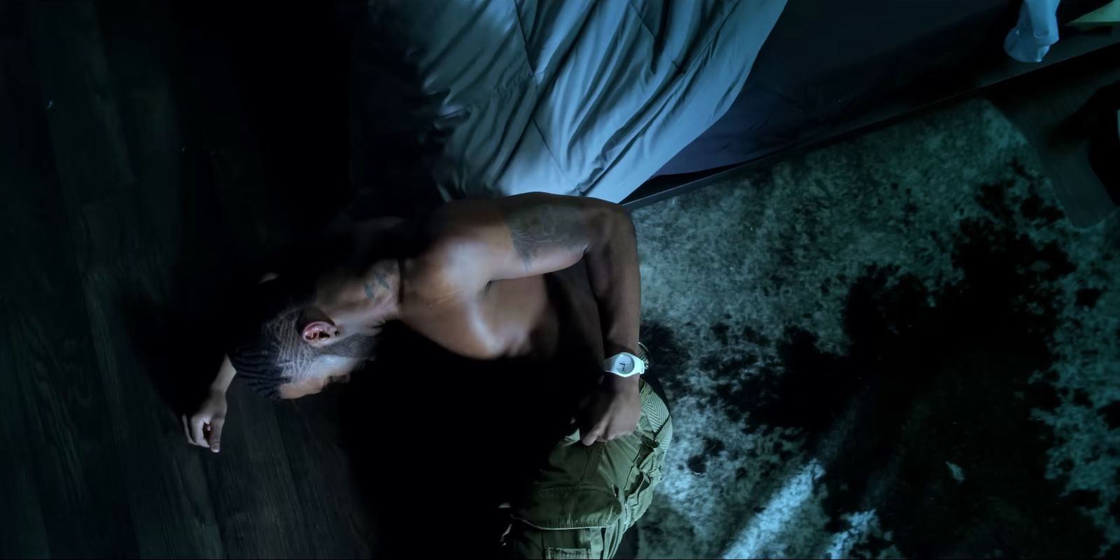 a shirtless man laying on a bed in the dark