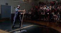 a man standing on top of a basketball court holding a broom