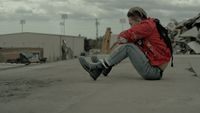 a boy sitting on the ground with a backpack on his back