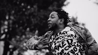 a black and white photo of a man with dreadlocks