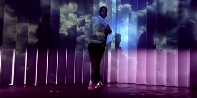 a man standing in front of a wall with clouds