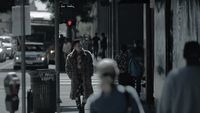 a woman walking down a street next to a traffic light