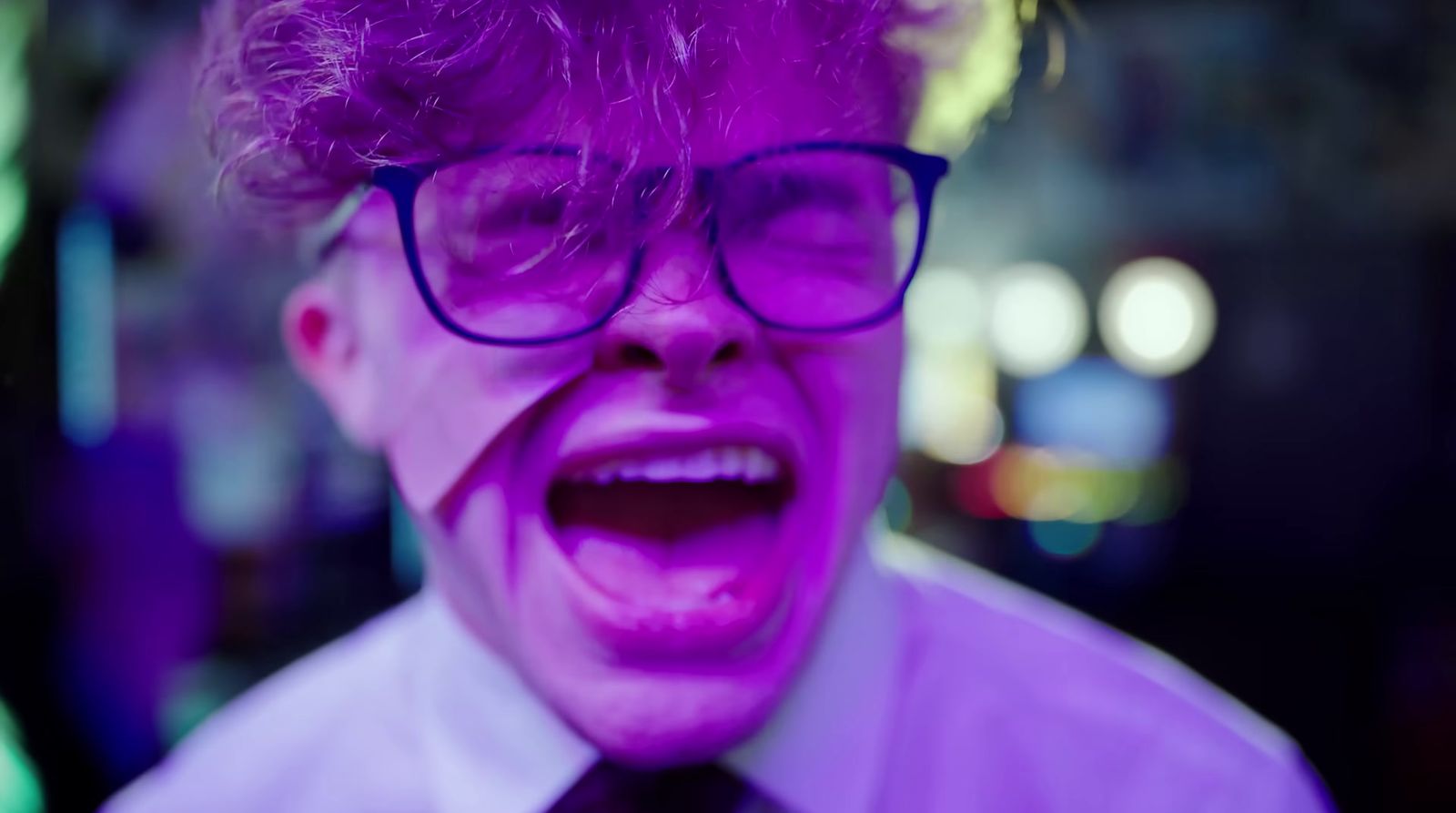 a man with purple hair and glasses making a face