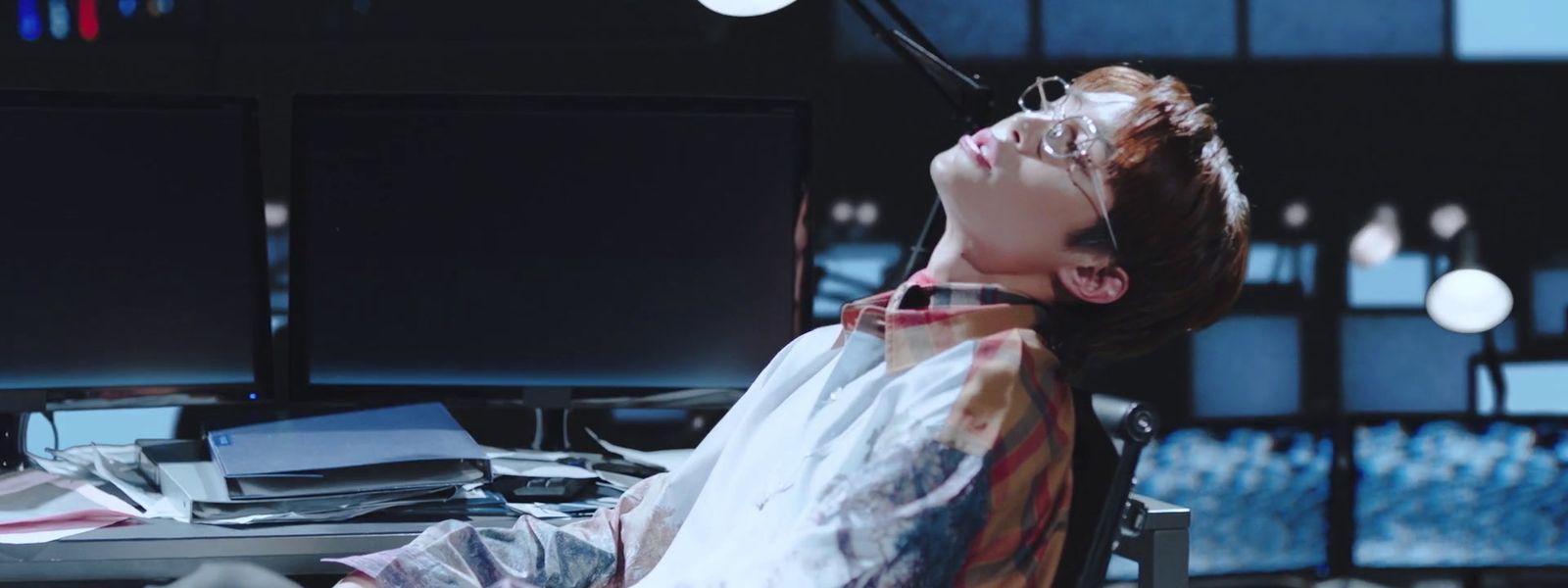 a man sitting at a desk in front of two computer monitors