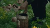 a person standing next to a watering can in a field