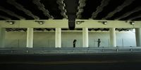 a couple of people standing under a bridge