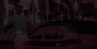 a man walking past a red car on a city street