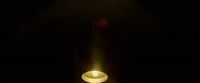 a lit candle in a dark room with a black background