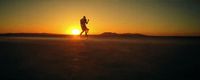 a man running across a field at sunset