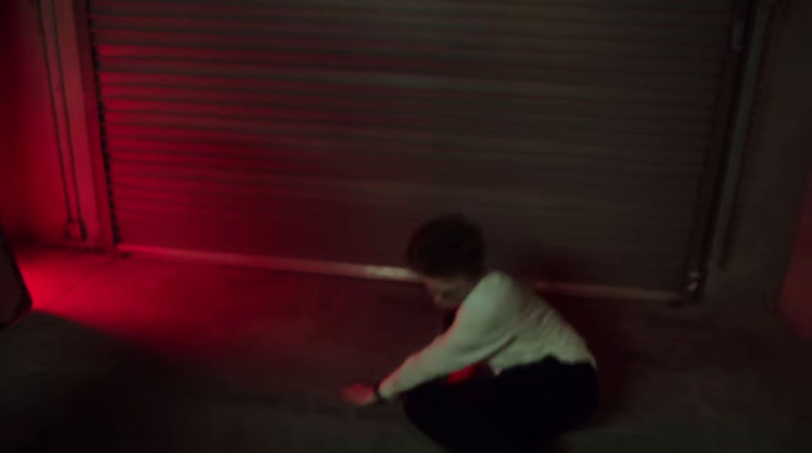 a young boy standing in front of a red light