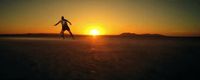 a man riding a skateboard across a field at sunset