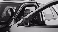 a man sitting in a car talking on a cell phone