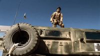 a man standing on top of a military vehicle