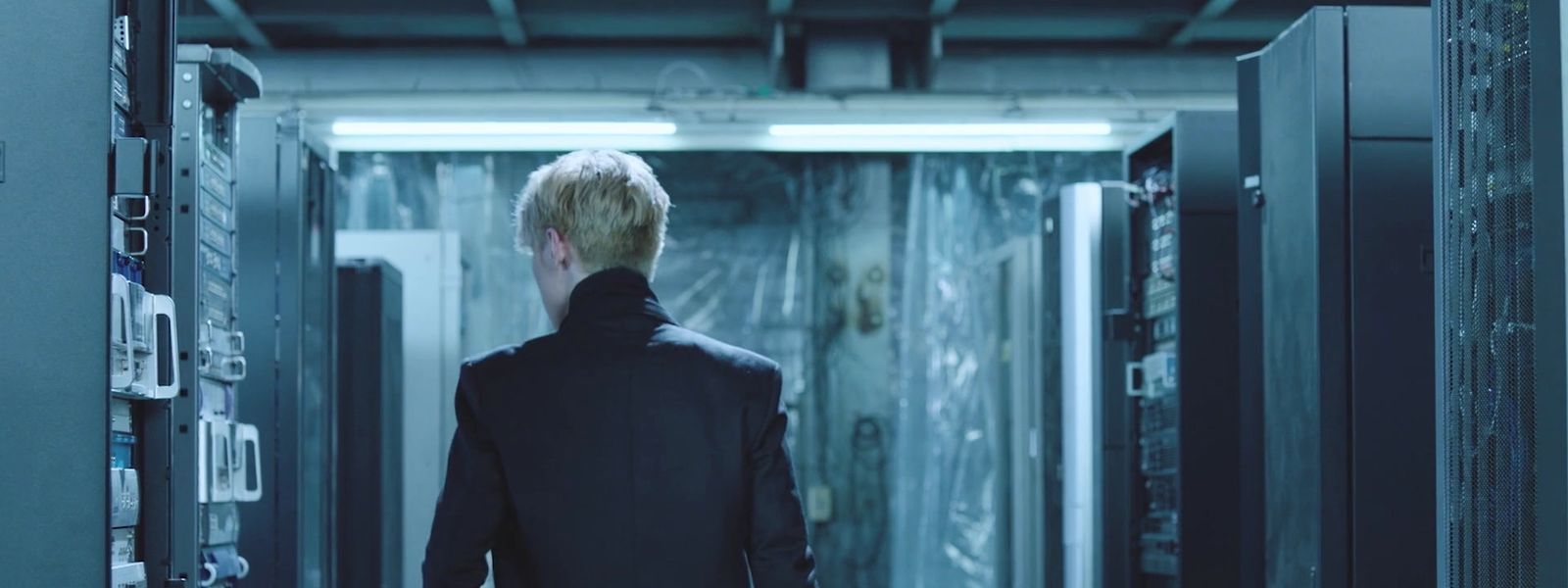 a man in a suit walks through a server room