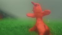 a blurry image of a red teddy bear in the grass