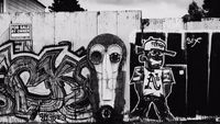 a black and white photo of graffiti on a fence