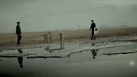 a couple of men standing next to a puddle of water