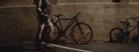 a man standing next to two bikes on a street