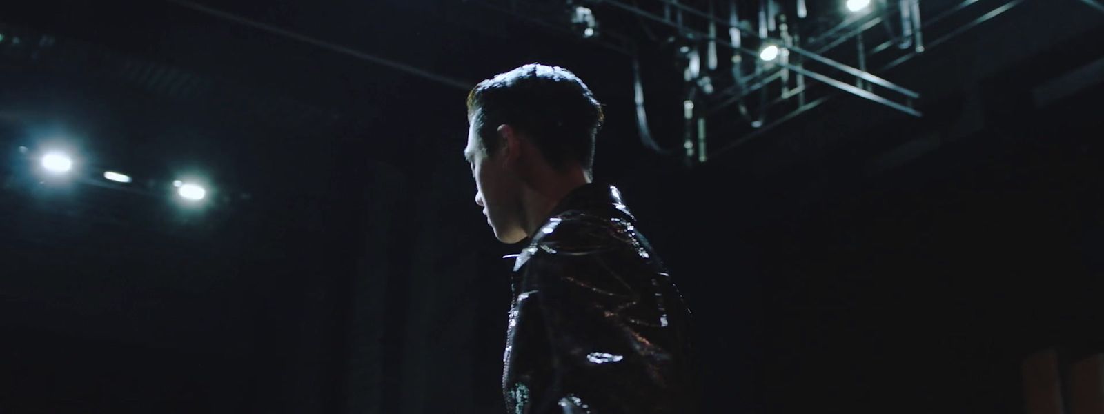 a man in a leather jacket standing in a dark room