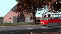 a red and gray bus driving down a street