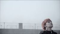 a woman with pink hair standing in front of a bridge