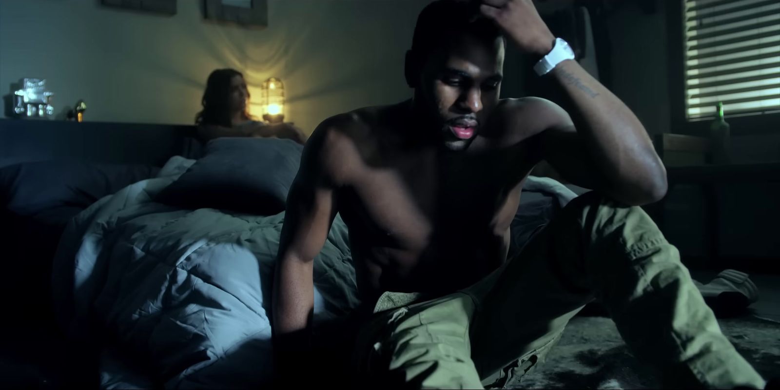 a shirtless man sitting on a bed in a bedroom