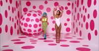 two women standing in front of a pink polka dot wall