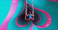 a girl sitting on a swing in a pink and blue sculpture