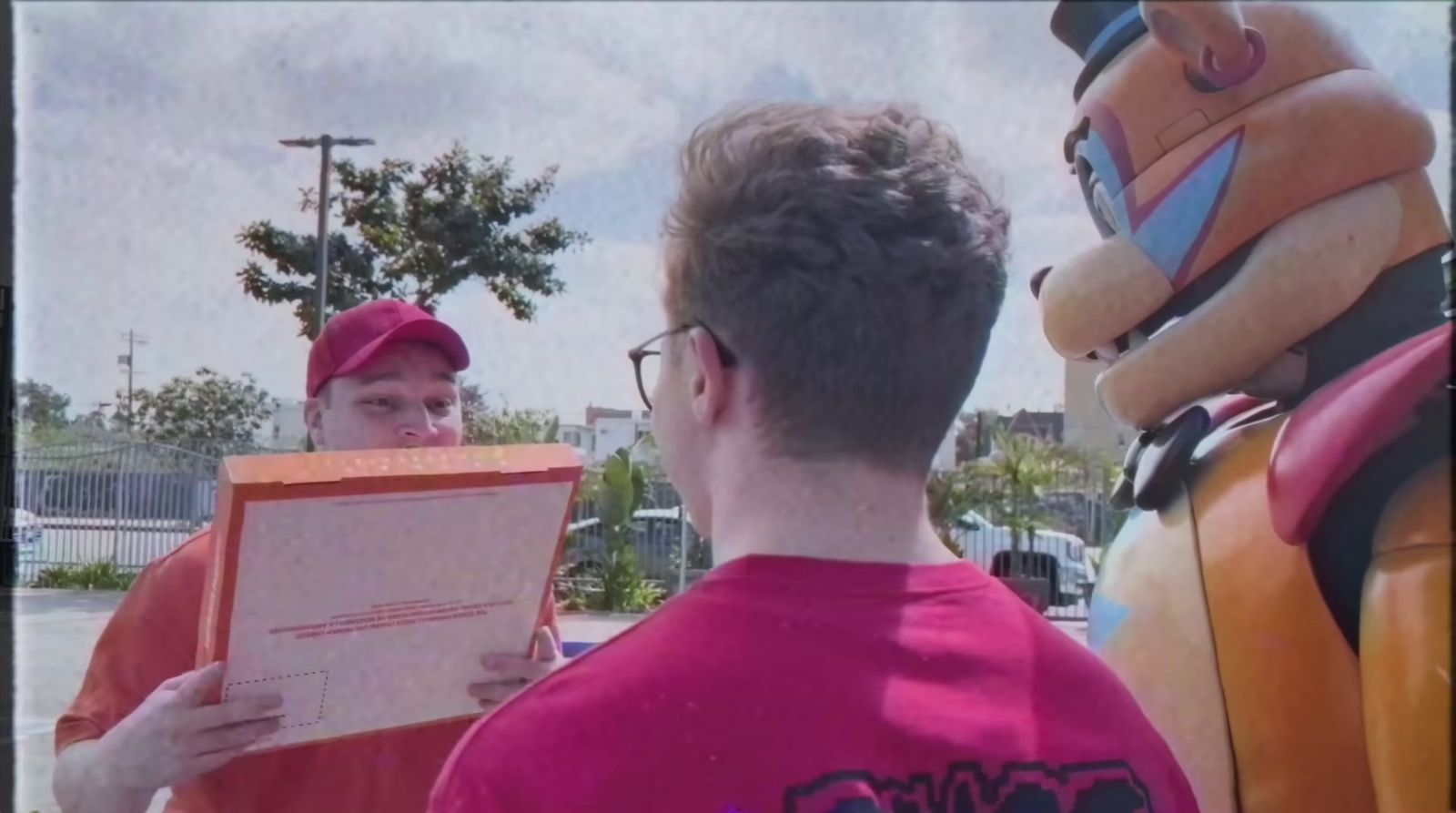 a man holding a piece of paper standing next to a man in a red shirt