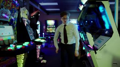 a man in a tie standing in front of a pinball machine