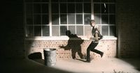 a man running past a trash can in front of a window