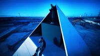 a man standing on top of a blue pyramid