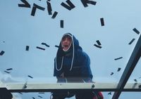 a man in a hoodie standing on a roof