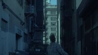 a man walking down a street next to tall buildings