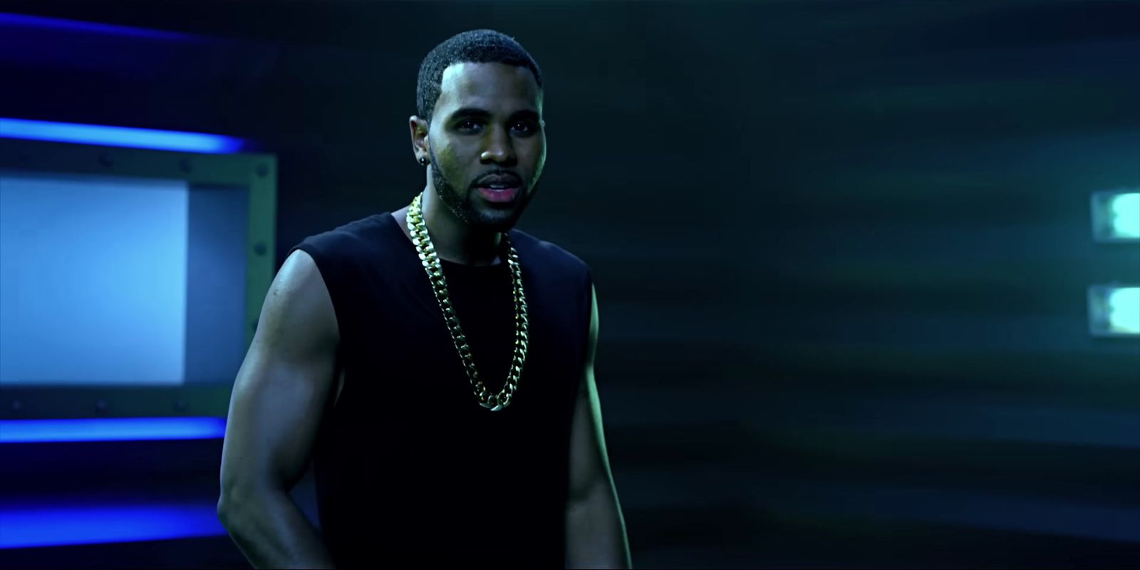 a man in a black tank top standing in a dark room