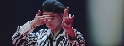 a man in a black and white striped shirt holding his hands up to his face