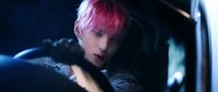 a man with pink hair driving a car