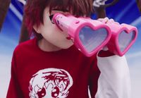 a person wearing a red shirt holding a pink heart shaped object