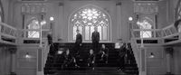 a black and white photo of a group of people sitting on a set of stairs