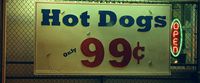 a sign advertising hot dogs on a chain link fence