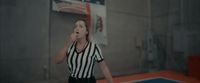 a woman in a referee's uniform standing on a basketball court