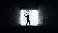 a person standing in a dark tunnel with their arms in the air