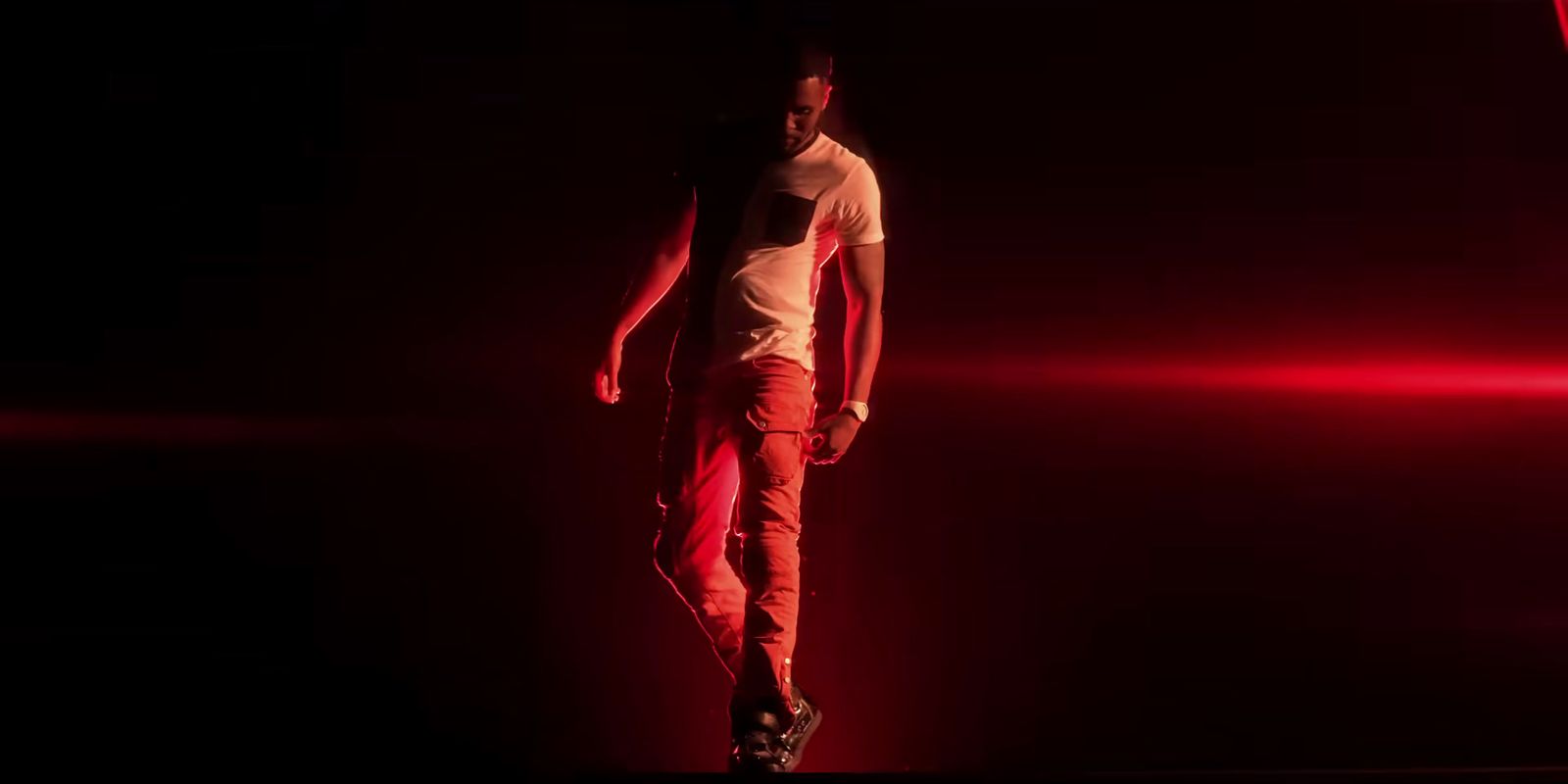 a man walking in the dark with a red light behind him