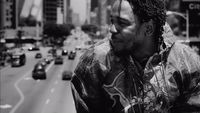 a black and white photo of a man with dreadlocks