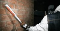 a person holding a baseball bat in front of a brick wall