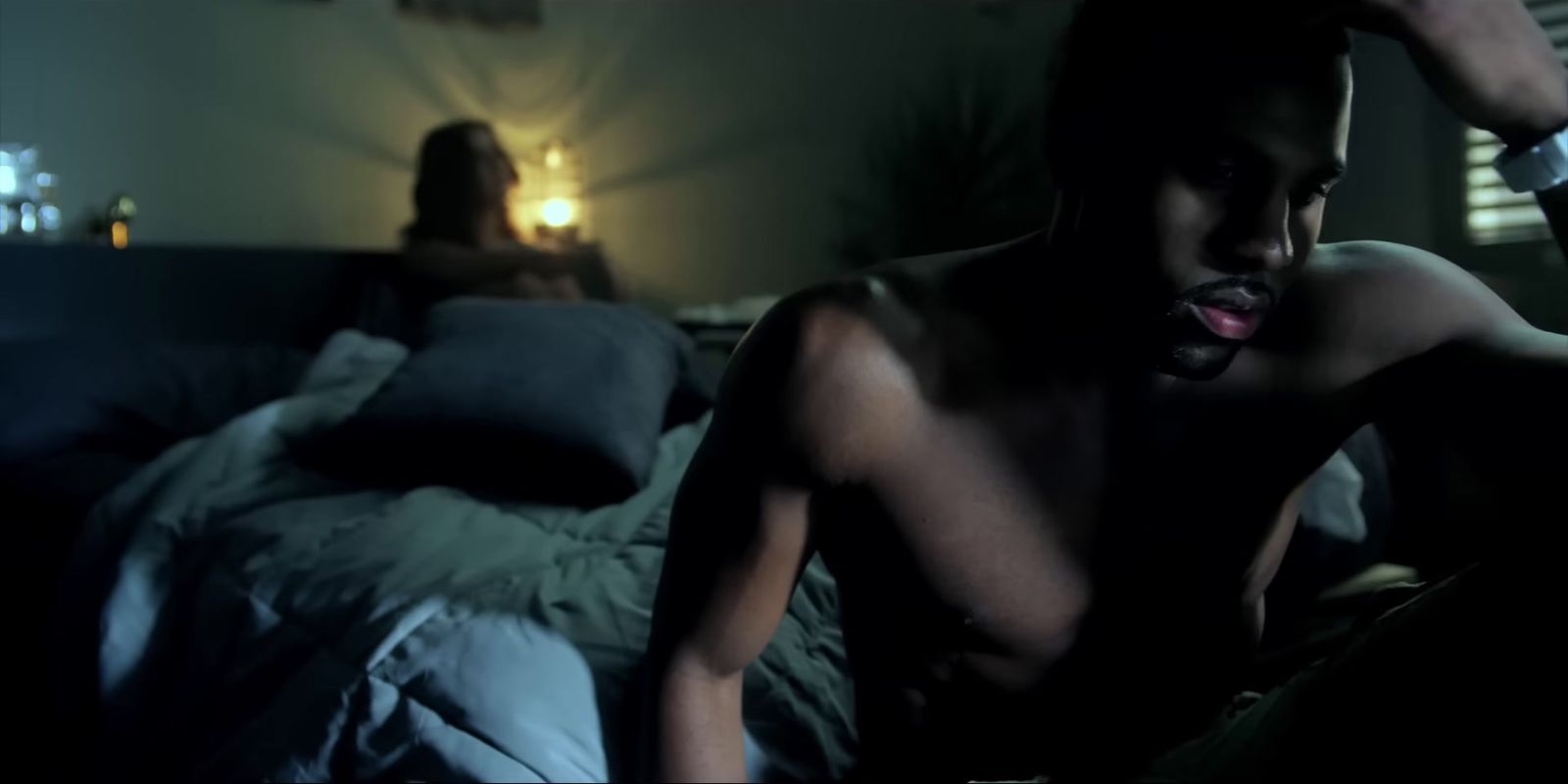 a shirtless man sitting on a bed next to a woman