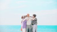 a group of people standing on top of a beach next to the ocean